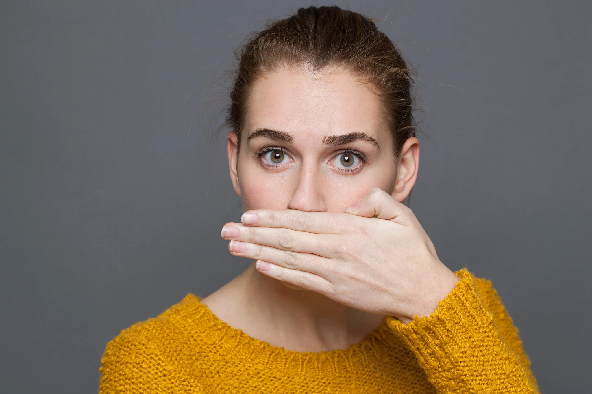 A woman covering her mouth, self-conscious about the bad breath that can come with weight-loss medications, a side effect the naturopathic team in South Tempe, AZ helps patients manage.
