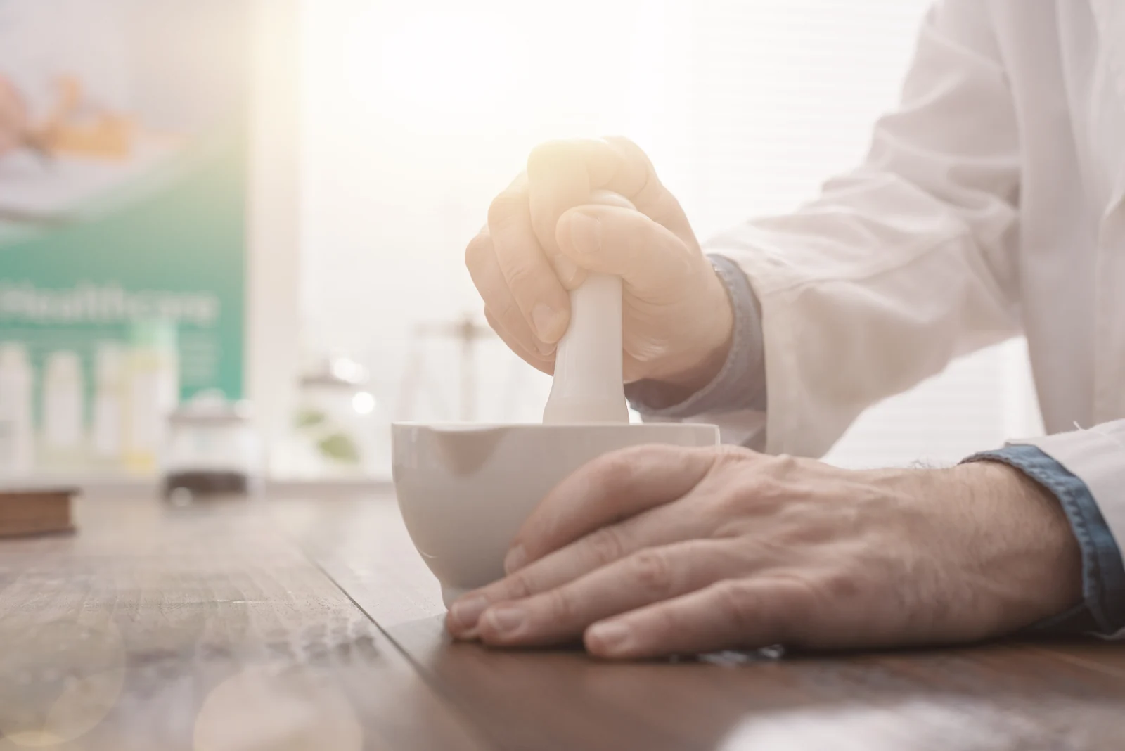 A pharmacist grinds a preparation with a mortar and pestle, showing how compounded medications are made in a pharmacy.