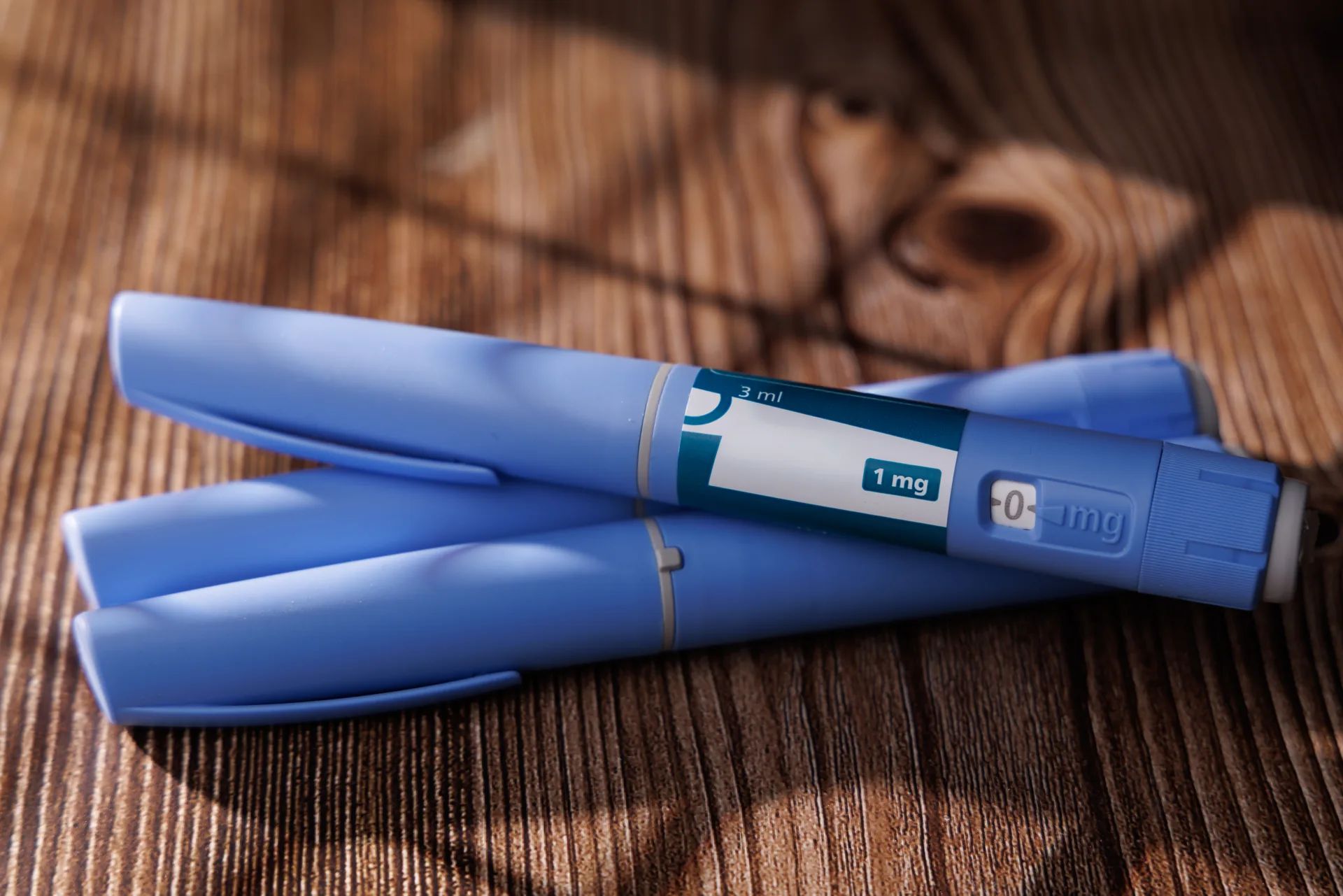 Two blue semaglutide-style injection pens on a wooden table, illustrating the GLP-1 medication discussed in this South Tempe, AZ guide to whether semaglutide works for weight loss.