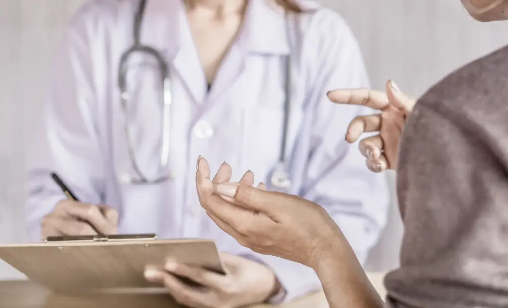 Woman describing her symptoms while a provider takes notes on a clipboard during a perimenopause visit in Tempe.