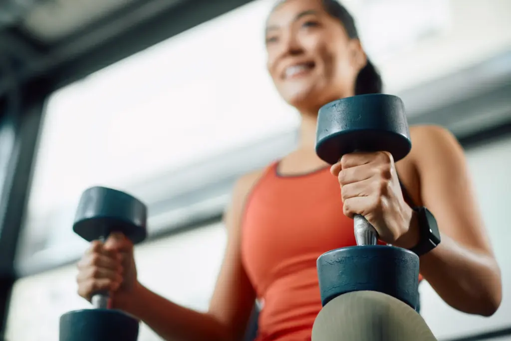 A woman lifting dumbbells during resistance training, reflecting the muscle-building movement that supports naturopathic weight loss in South Tempe, AZ.