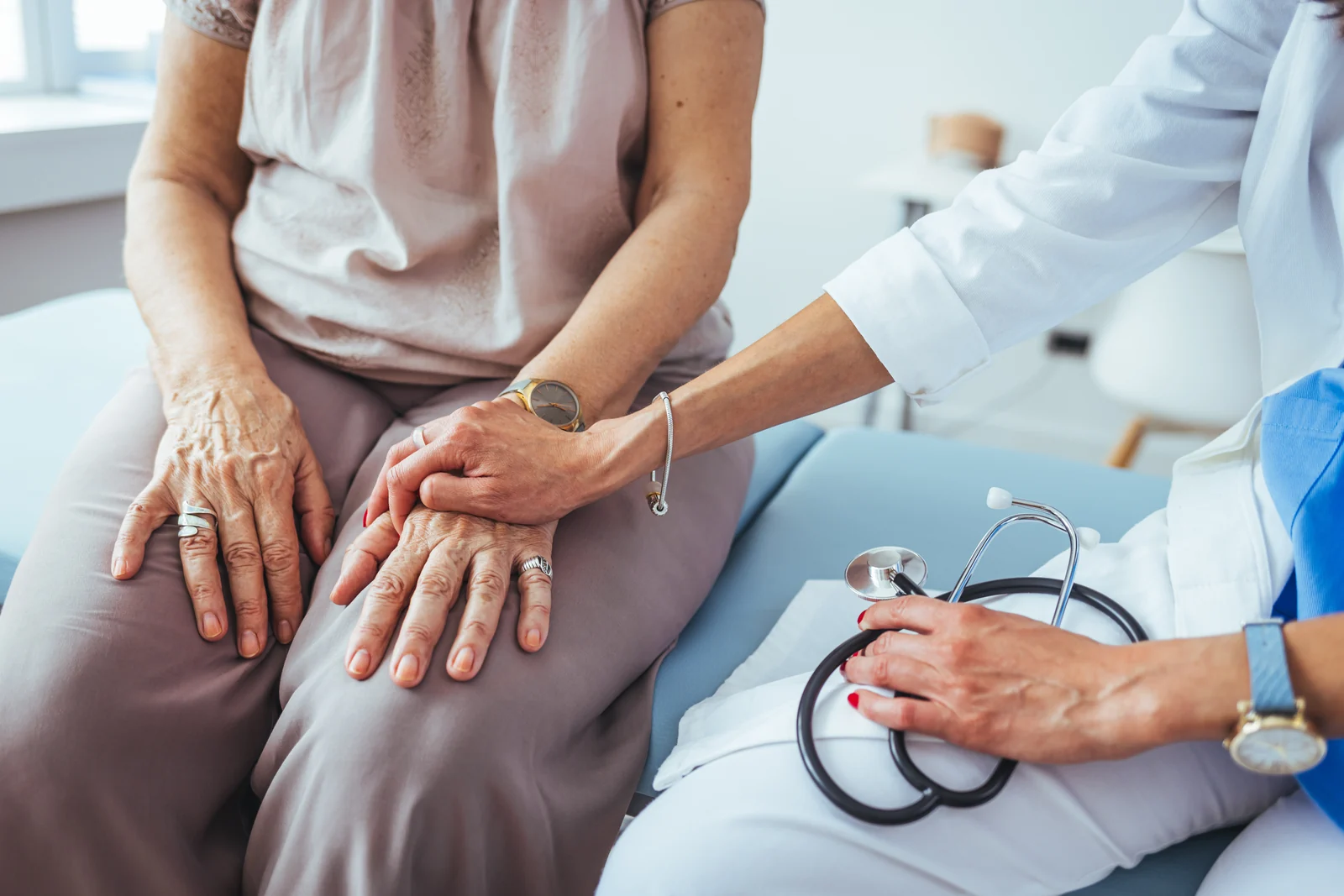 Provider gently holding the hands of a mature woman patient beside a stethoscope during a private consultation in South Tempe, AZ.