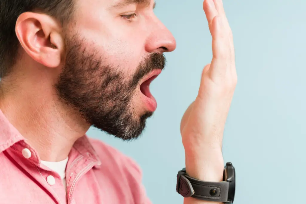 A man cupping his hand to check his breath, an example of the bad breath some people notice on semaglutide and other weight-loss medications in South Tempe, AZ.