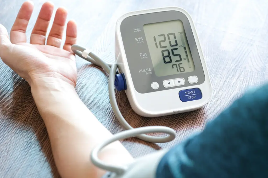 Man checking his blood pressure with a home monitor, since healthy blood flow and heart health are closely tied to erectile function.