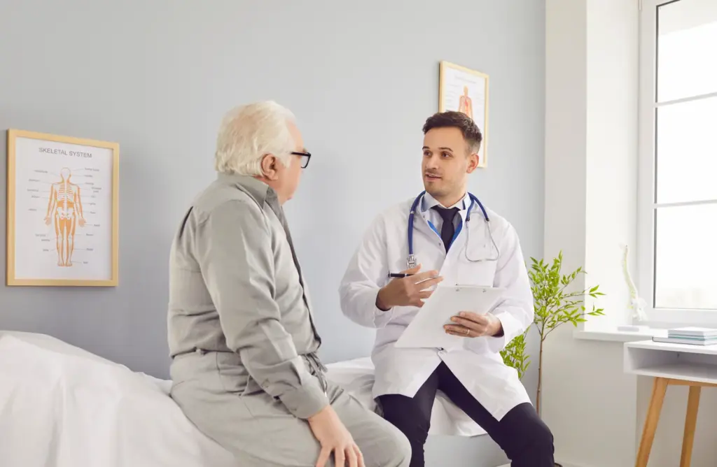 A mature male patient discussing treatment options with a doctor in a clinic, reflecting the consultation that decides candidacy for shockwave therapy for ED in South Tempe, AZ.