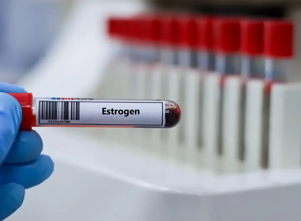Gloved hand holding a blood sample tube labeled for an estrogen test, used to check hormone levels during perimenopause.