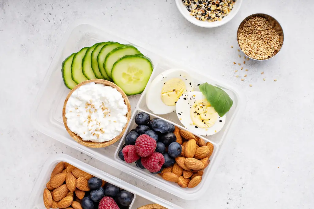 High protein snack box with boiled eggs, cottage cheese, nuts and berries to help protect skin and muscle during weight loss.