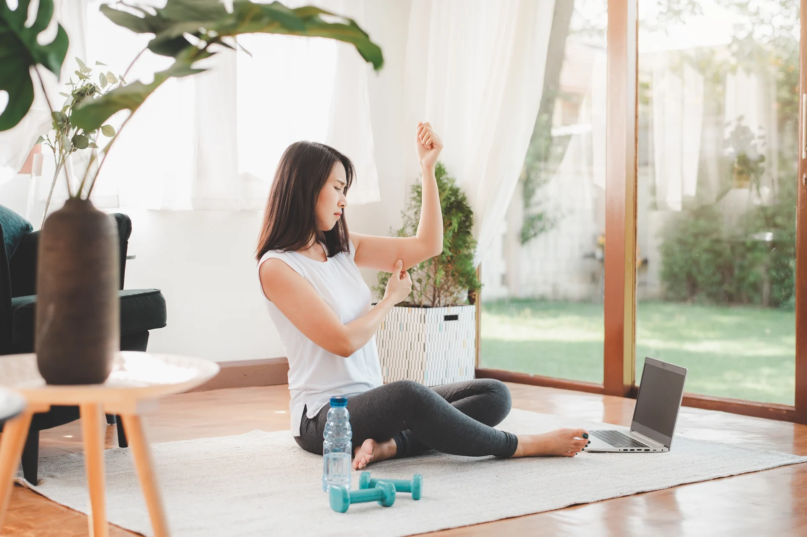 Woman at home pinching loose skin on her upper arm, a common concern after rapid weight loss for patients in South Tempe, AZ.