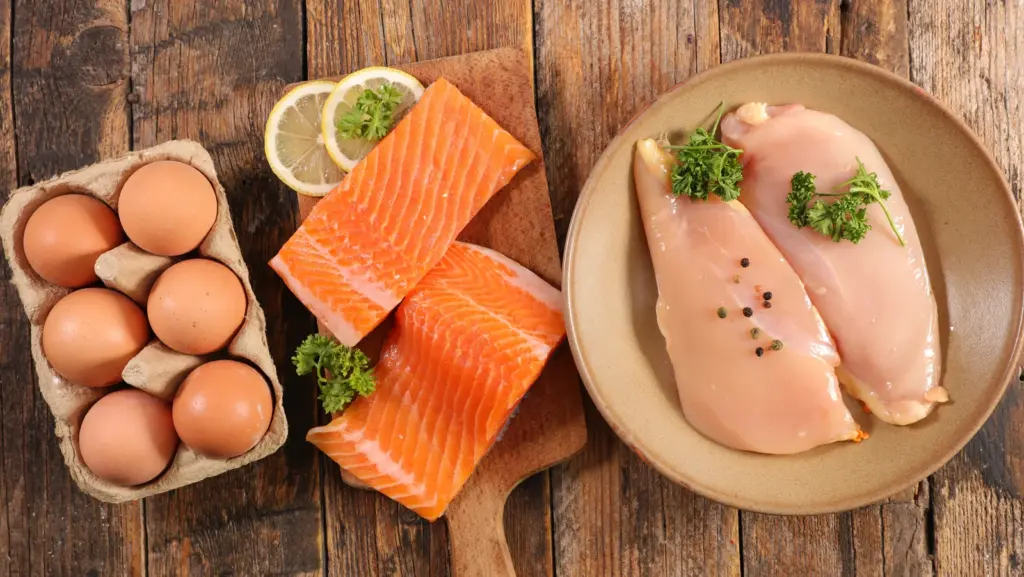 Eggs, fresh salmon, and chicken breast on a wooden table, protein-rich foods that support hair while losing weight in Tempe.
