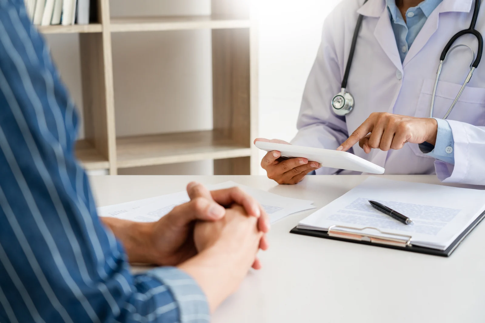 Provider with a stethoscope reviewing records on a tablet with a patient across a desk during a consultation at a wellness center in South Tempe, AZ.