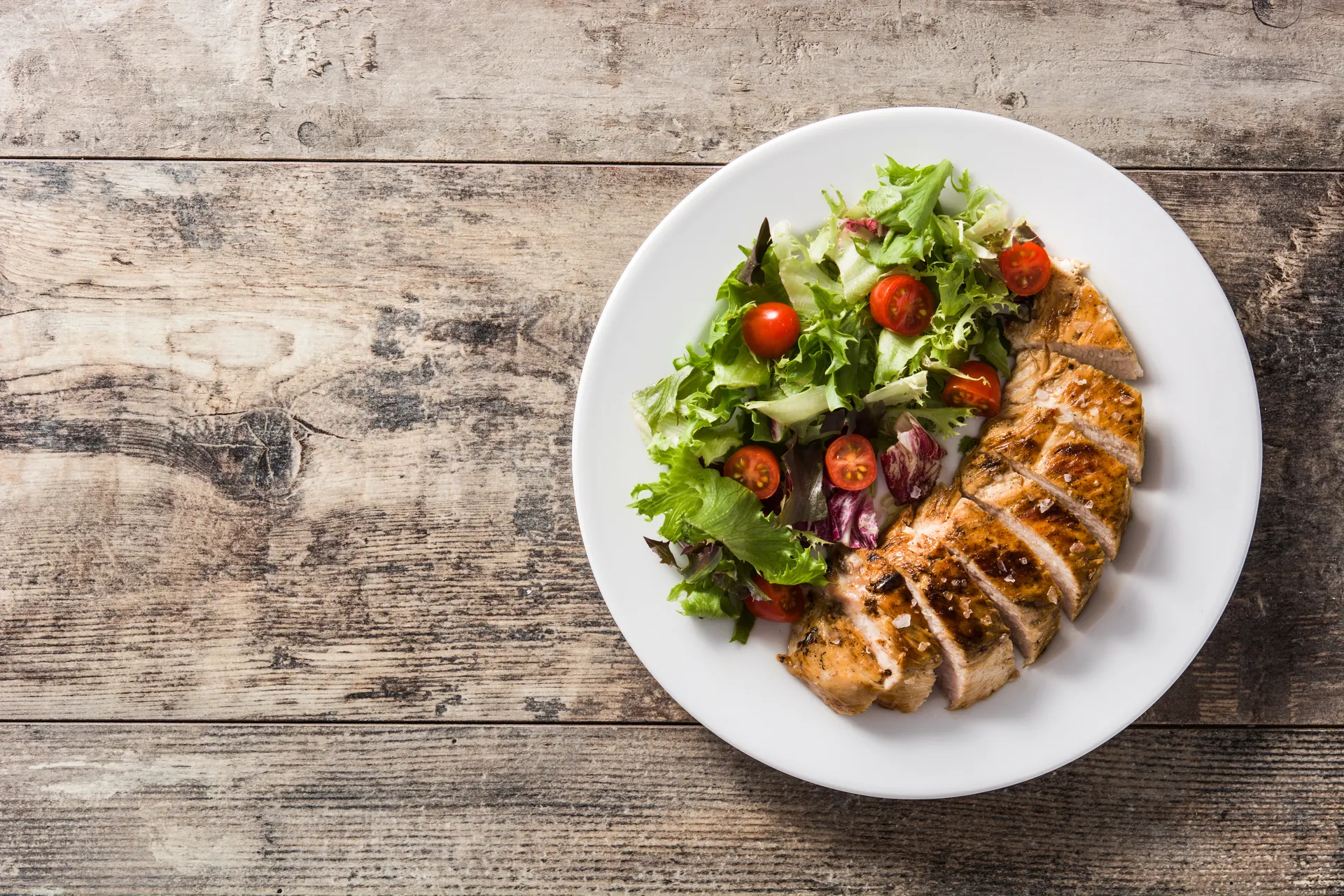 A plate of sliced grilled chicken breast with a fresh green salad, showing the protein-first meals recommended while taking semaglutide, from a South Tempe, AZ naturopathic clinic.
